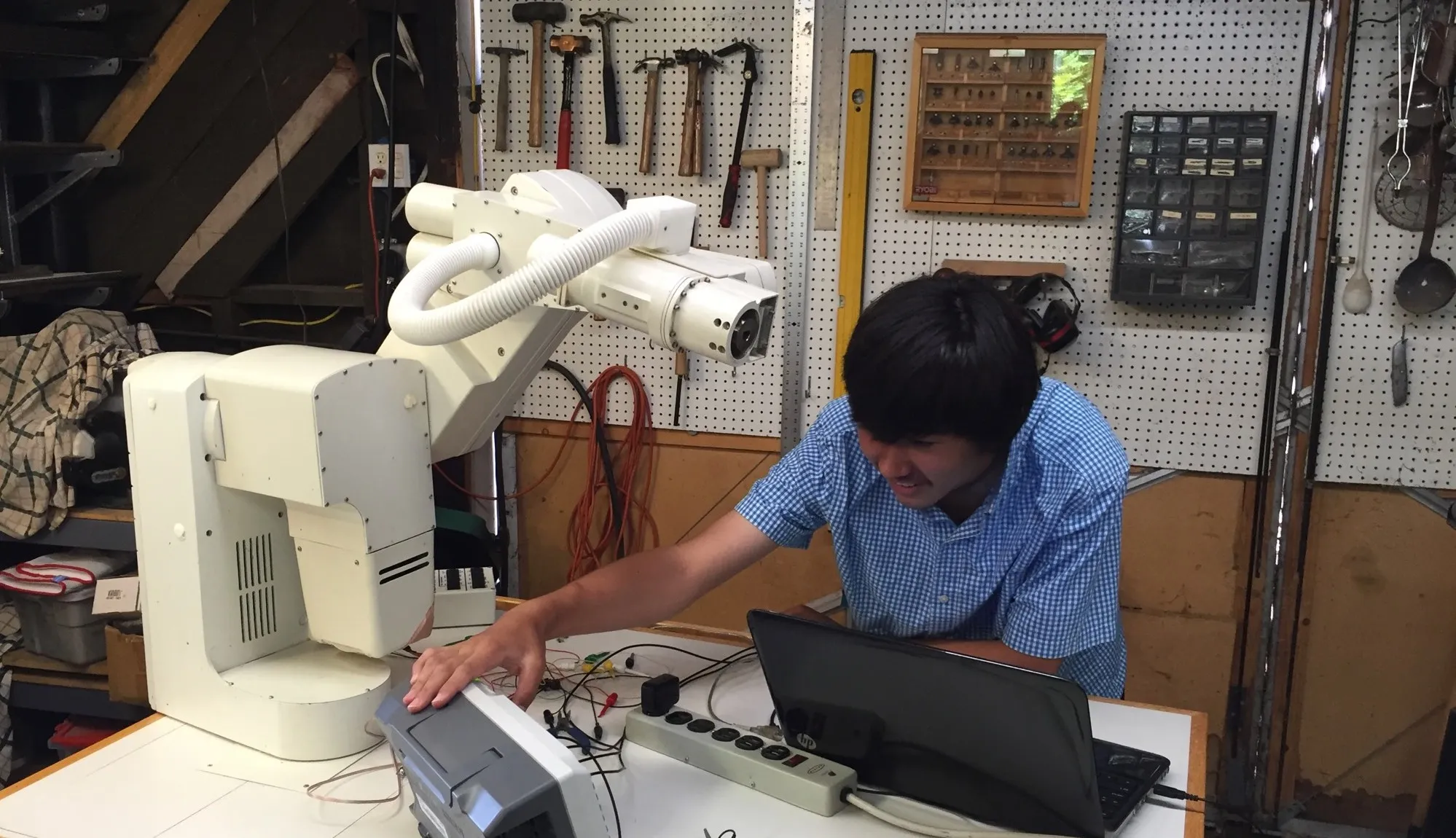 Student programming a robot arm with a laptop in the Robot Garage